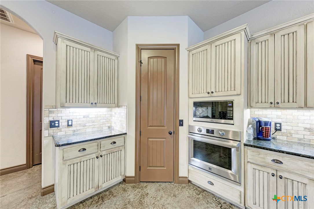 1325 County Road 106 Lampasas, TX 76550 - Photo 10 of 48 a kitchen with stainless steel appliances granite countertop a stove a sink and a refrigerator with wooden cabinets
