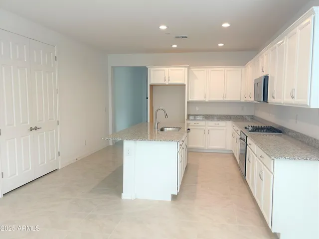 a kitchen with a sink a stove top oven and white cabinets