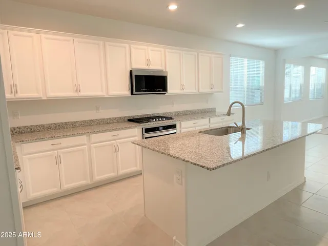 a kitchen with granite countertop white cabinets and white appliances