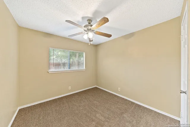 an empty room with a window and a fan
