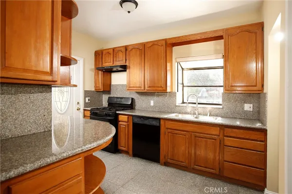 a kitchen with granite countertop sink stove and cabinets