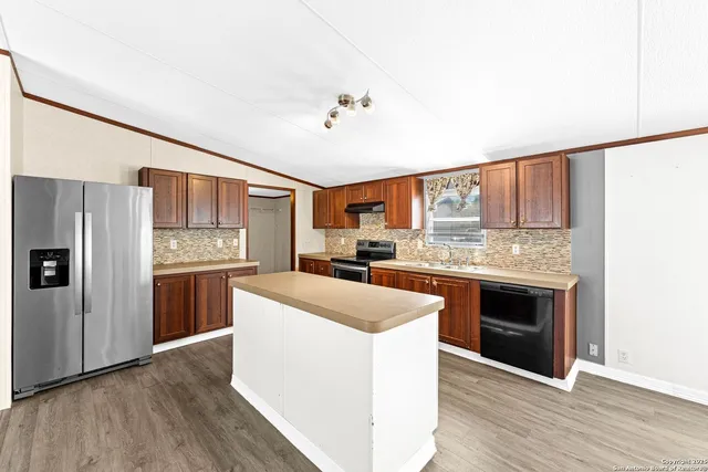 a kitchen with stainless steel appliances granite countertop a refrigerator a stove a sink and white cabinets with wooden floor