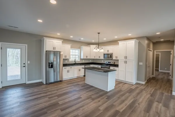 a kitchen with stainless steel appliances kitchen island granite countertop a refrigerator and a sink