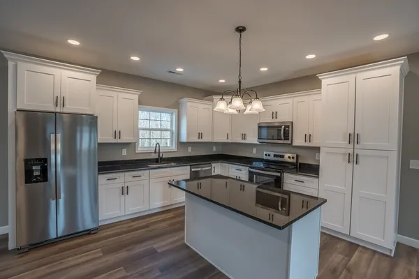 a kitchen with stainless steel appliances granite countertop a sink refrigerator and microwave