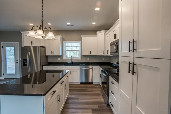 a kitchen with kitchen island granite countertop a sink stove and refrigerator