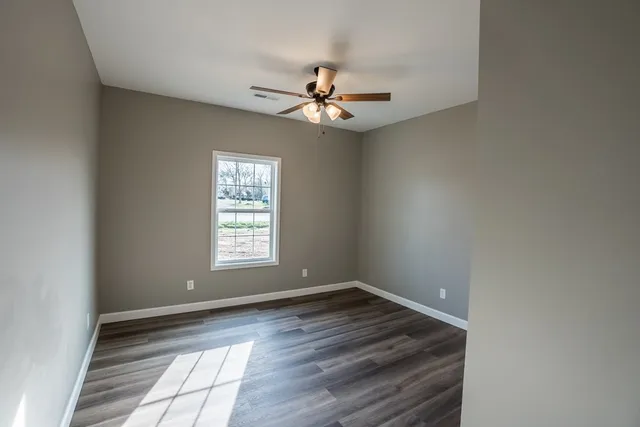 a view of a hallway with wooden floor and a chandelier fan