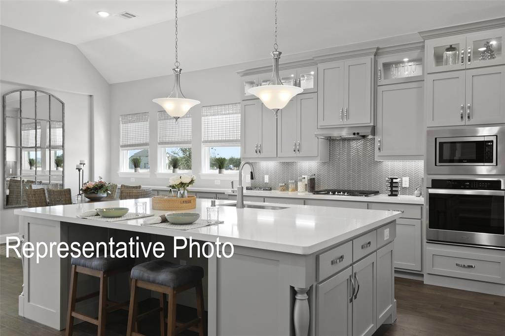 331 Fire Blade Drive Aledo, TX 76008 - Photo 3 of 17 Spacious kitchen featuring a large central island with seating, pendant lighting, built-in stainless steel appliances, and extensive cabinetry with undermount lighting