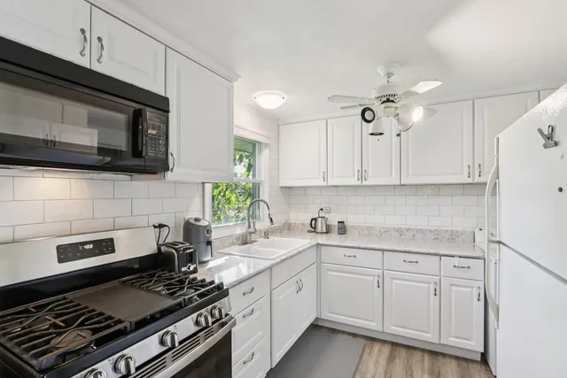 a kitchen with cabinets stainless steel appliances and wooden floor