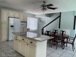 1034 Bali Road Cocoa Beach, FL 32931 - Photo 11 of 40 a kitchen with granite countertop a table chairs stove and refrigerator