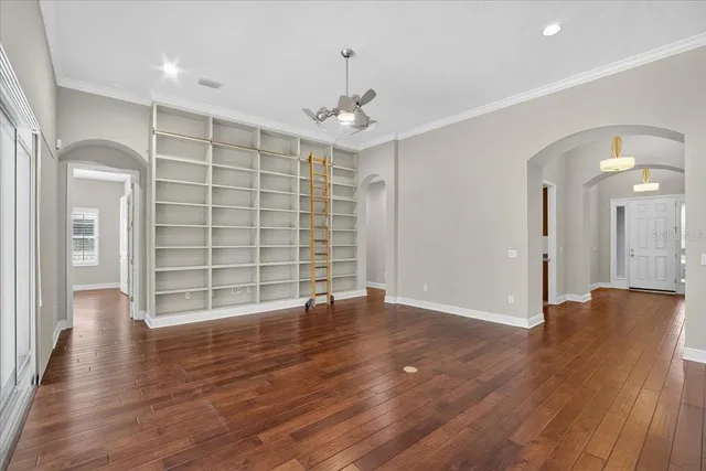 an empty room with wooden floor cabinet and windows