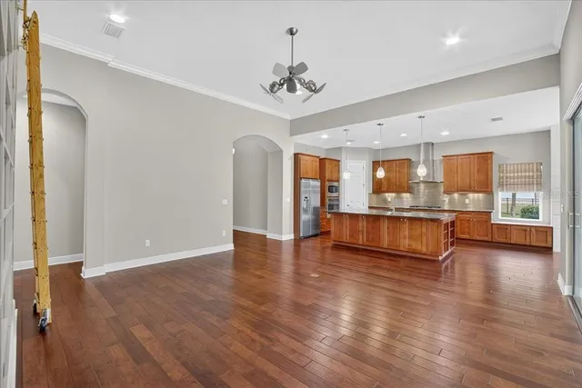 a view of an empty room with wooden floor and a kitchen