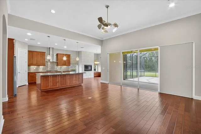 a living room with stainless steel appliances kitchen island hardwood floor and a large window