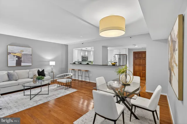 a living room with furniture kitchen view and a wooden floor