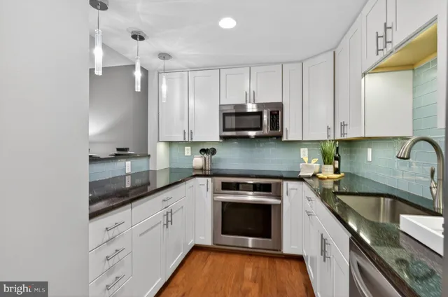 a kitchen with stainless steel appliances granite countertop white cabinets granite counter tops and a hard wood floors