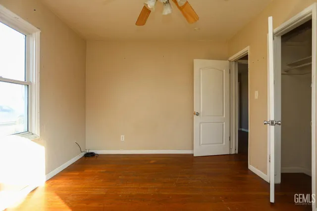 a view of an empty room with window and chandelier fan