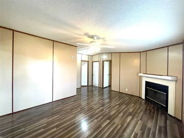 an empty room with wooden floor fireplace and windows