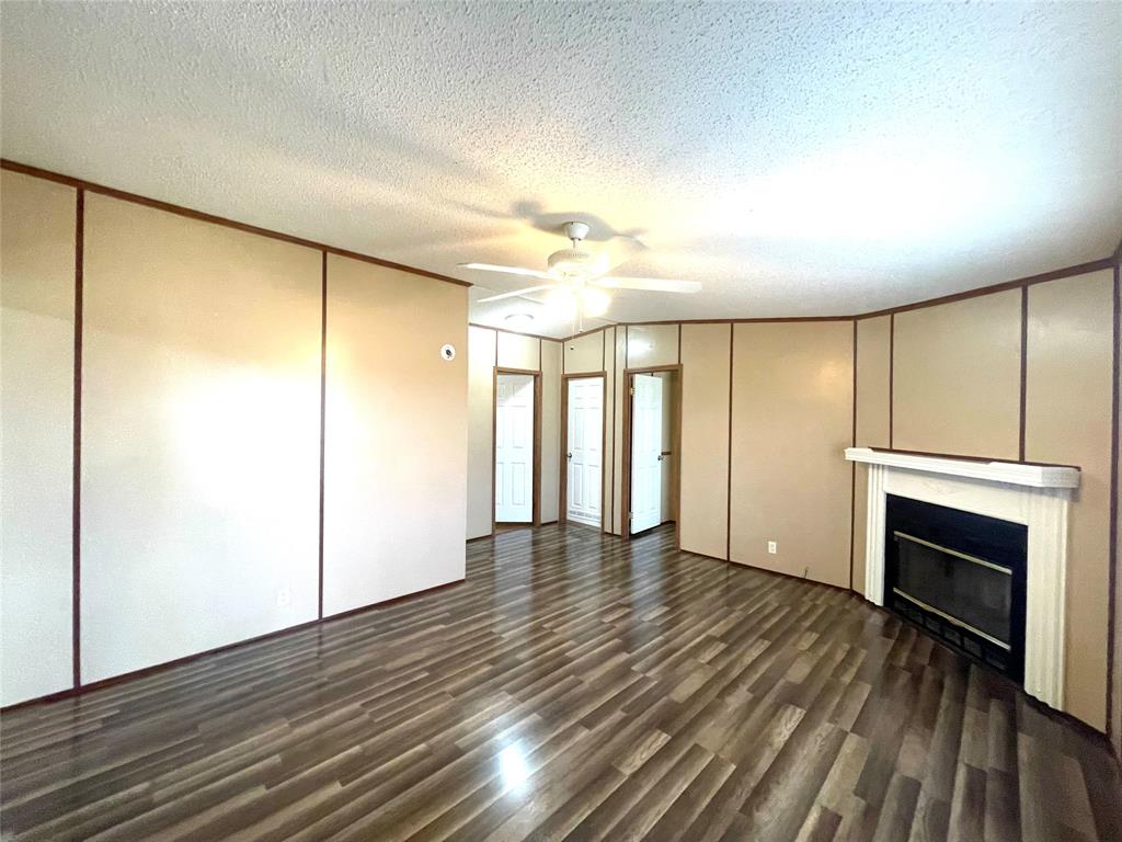 440 Ballman Road Riesel, TX 76682 - Photo 16 of 32 an empty room with wooden floor fireplace and windows