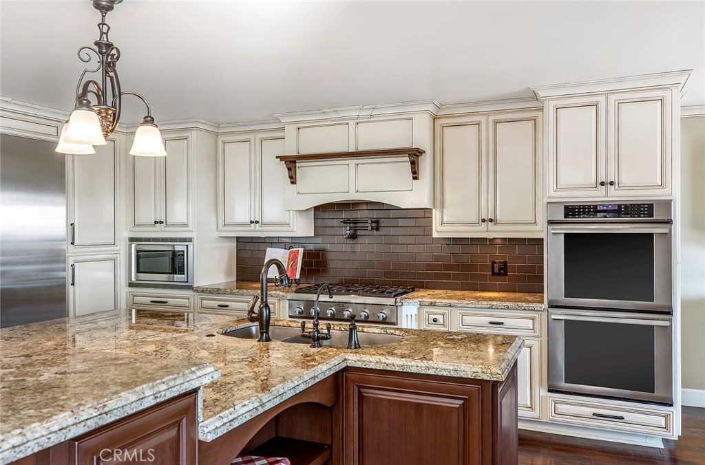 12822 Periwinkle Drive North Tustin, CA 92705 - Photo 17 of 36 a kitchen with stainless steel appliances granite countertop a stove a sink and a microwave