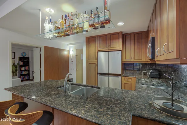 a kitchen with kitchen island granite countertop a sink stainless steel appliances and cabinets