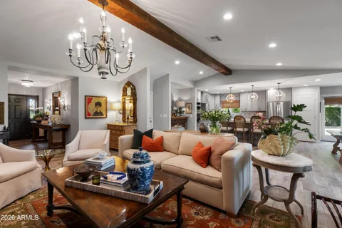 a living room with furniture kitchen view and a chandelier