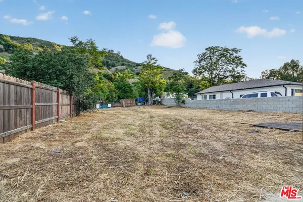 a view of a yard with wooden fence