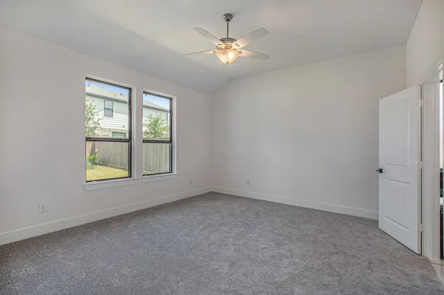 an empty room with windows and fan