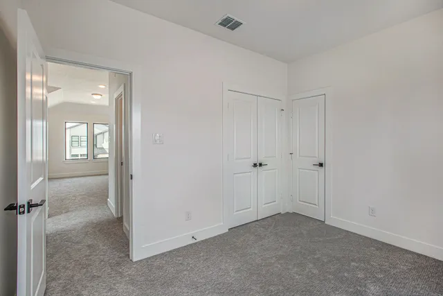 a view of an empty room with closet and a bathroom