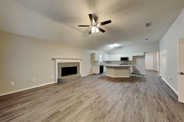 a view of empty room with wooden floor and fireplace