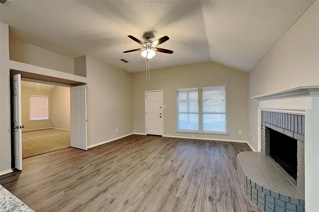 an empty room with wooden floor a ceiling fan and windows