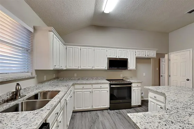 a kitchen with granite countertop a sink stove and refrigerator