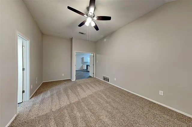a view of an empty room with window and ceiling fan
