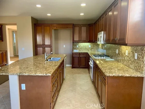 a kitchen with kitchen island granite countertop a sink a counter top space and stainless steel appliances
