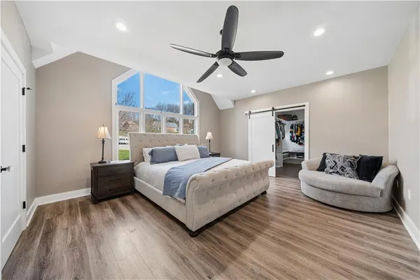a spacious bedroom with a bed couch and window