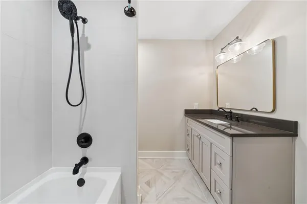a bathroom with a granite countertop sink a mirror and shower