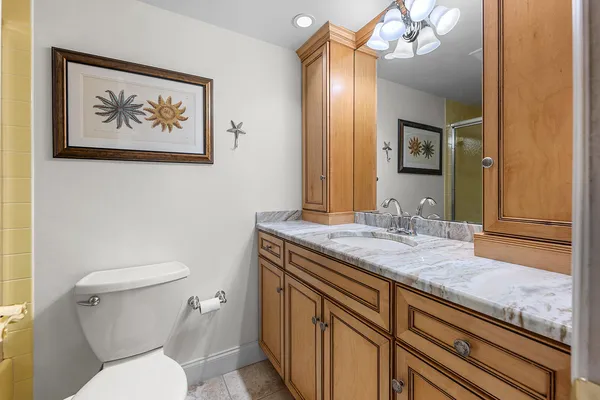 a bathroom with a granite countertop toilet a sink and a large mirror