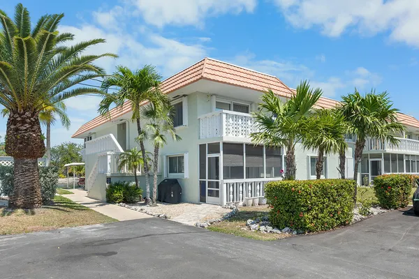 a view of a white house with a large window and potted plants