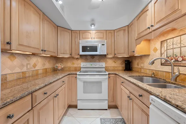 a kitchen with granite countertop white cabinets and white appliances