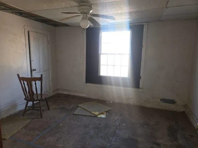 an empty room with windows and fan