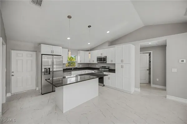 a kitchen with stainless steel appliances granite countertop a refrigerator a stove a sink and a microwave