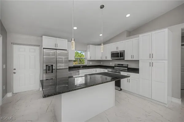 a kitchen with granite countertop white cabinets and a stove a oven with white countertops