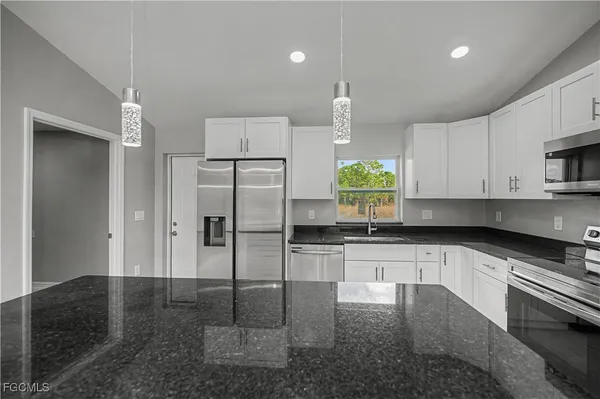 a kitchen with white cabinets stainless steel appliances and a sink