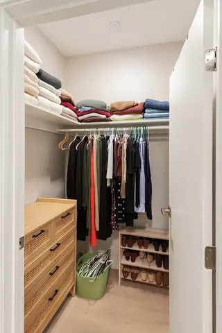 a view of walk in closet with clothes and shoes