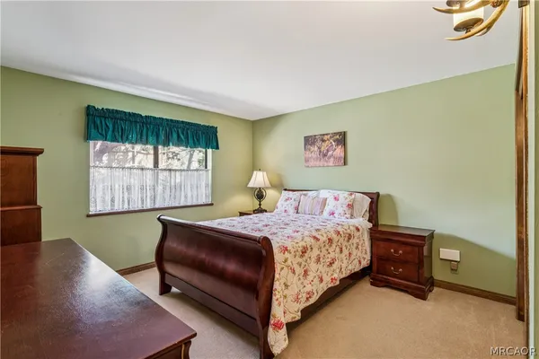 a bedroom with a bed and a lamp on dresser