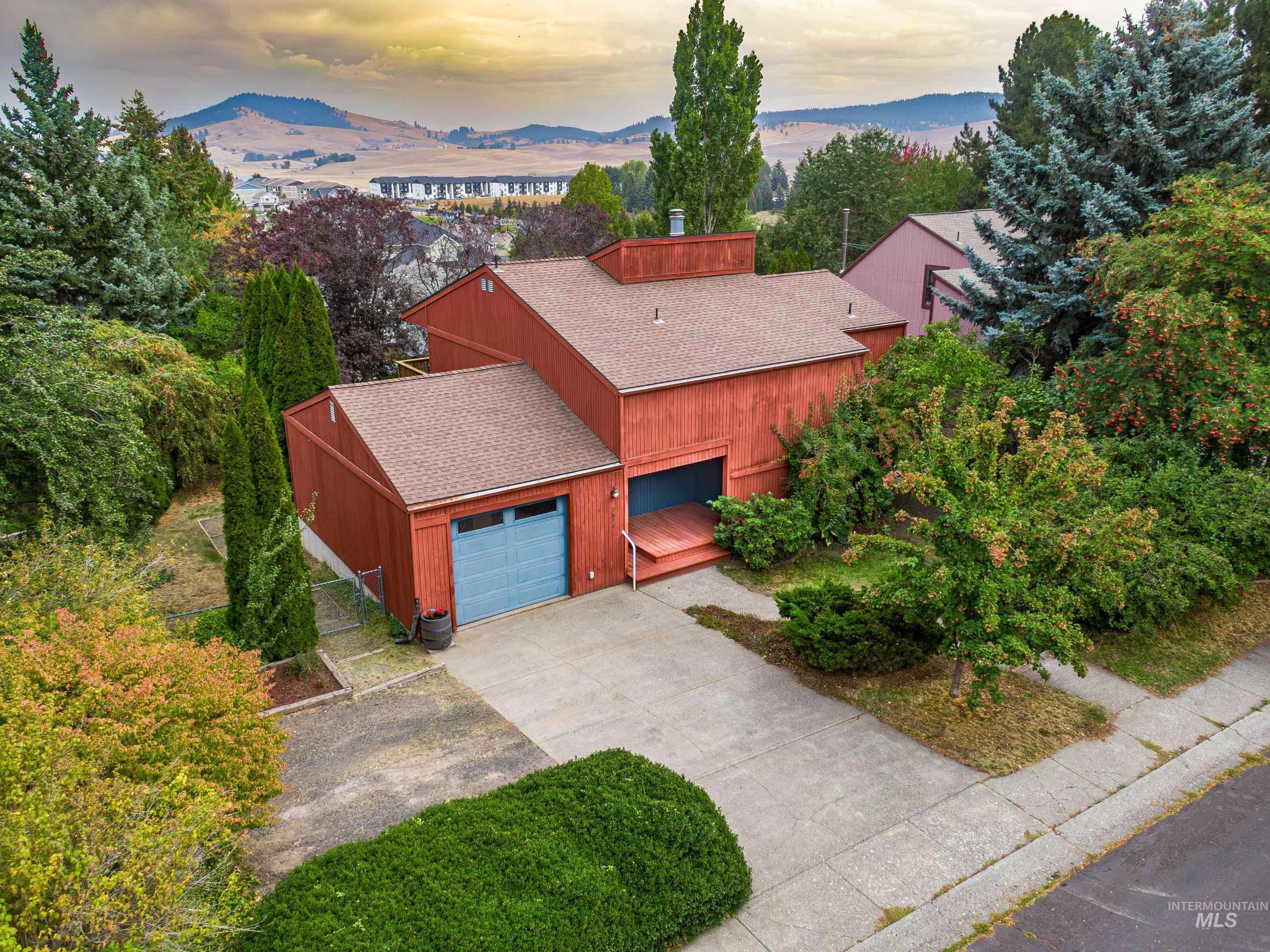 1614 Pine Cone Road Moscow, ID 83843 - Photo 1 of 1 Aerial view of property and surrounding area featuring a tree filled landscape and a mountain backdrop
