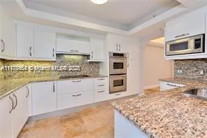 a large kitchen with granite countertop a sink and dishwasher a stove top oven with wooden floor