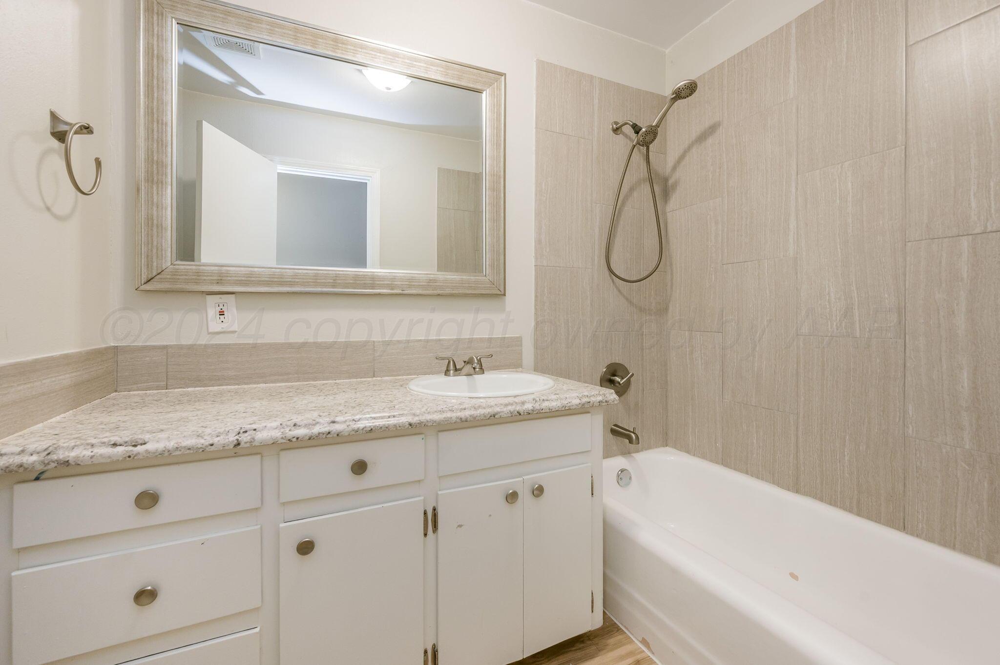 4207 South Ong Street Amarillo, TX 79110 - Photo 12 of 16 a bathroom with a granite countertop sink a toilet and a bathtub