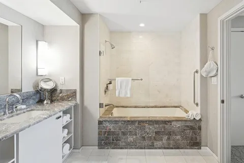 a bathroom with a granite countertop sink a mirror and shower