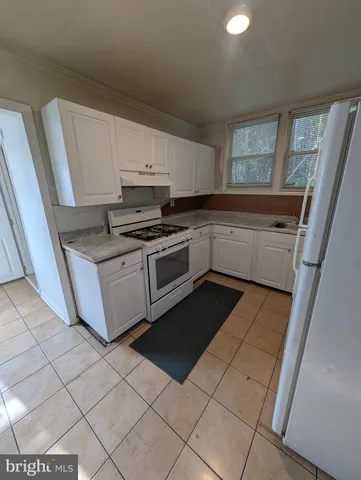 a kitchen with a sink a stove top oven and white cabinets