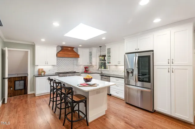 a kitchen with a refrigerator a stove a sink and a dining table with wooden floor