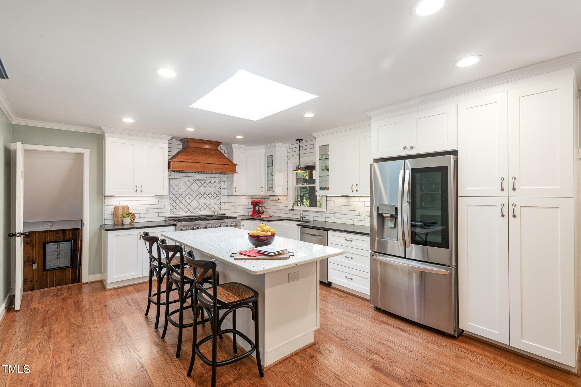 a kitchen with a refrigerator a stove a sink and a dining table with wooden floor